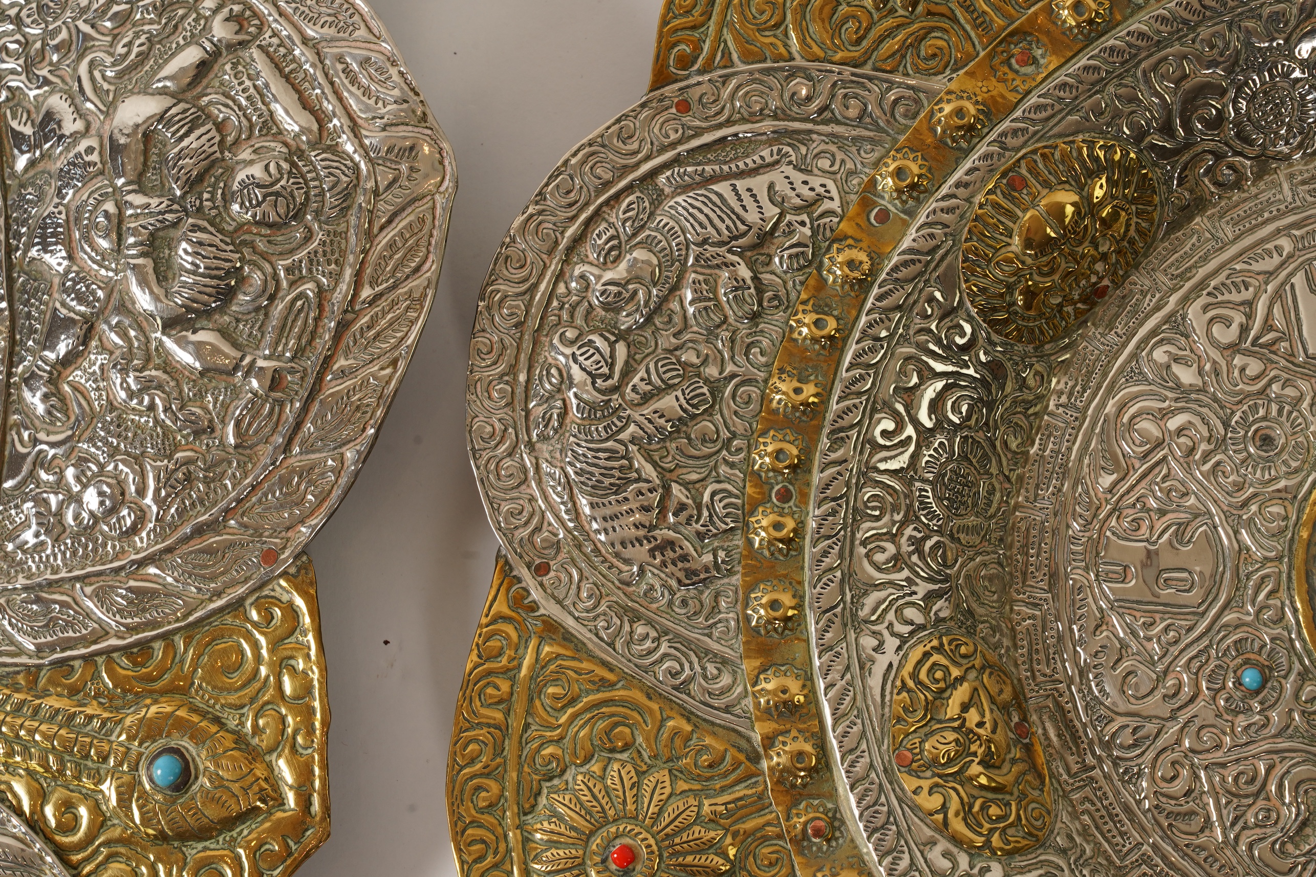 A graduated set of three Nepalese repoussé white metal and brass chargers, first half 20th century